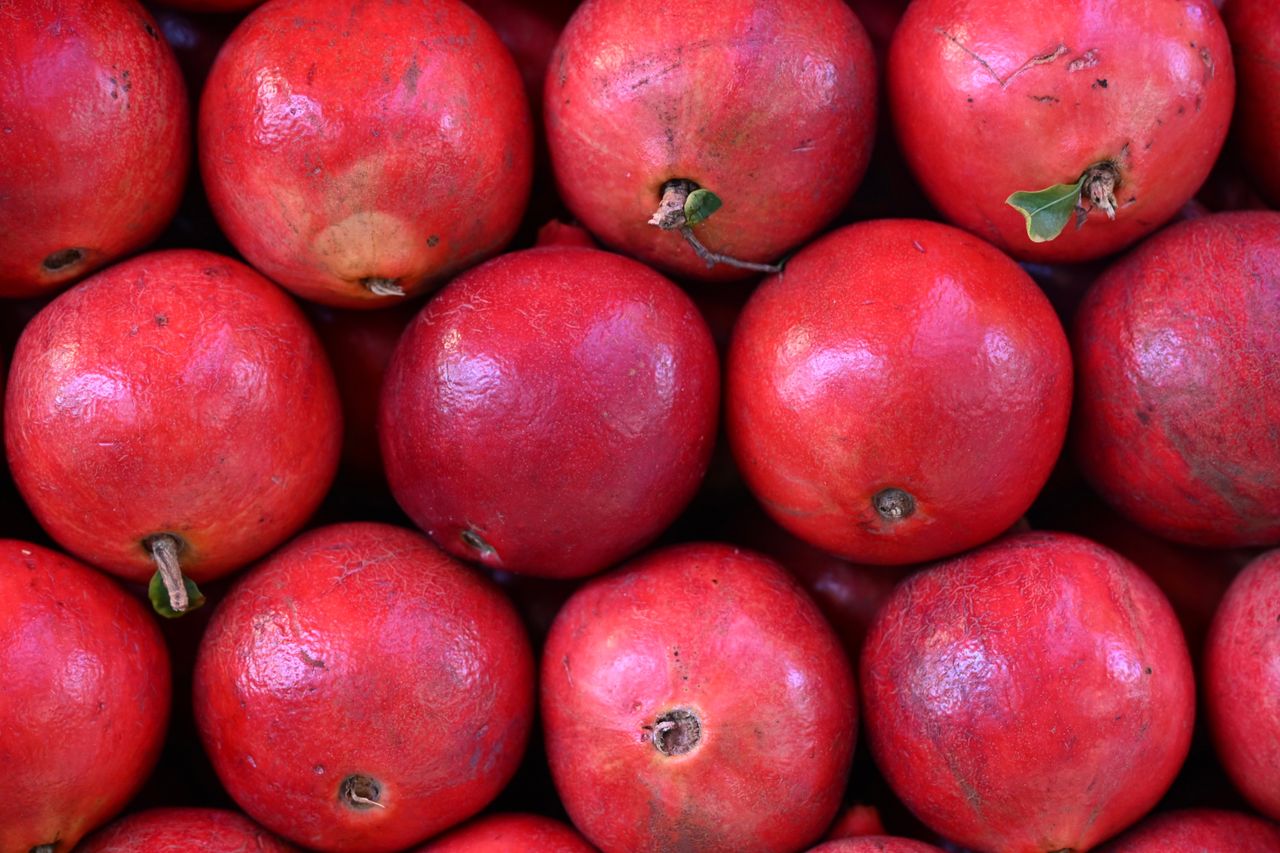 services-01 Fresh red pomegranates stacked at a market, showcasing their vibrant color and organic nature.