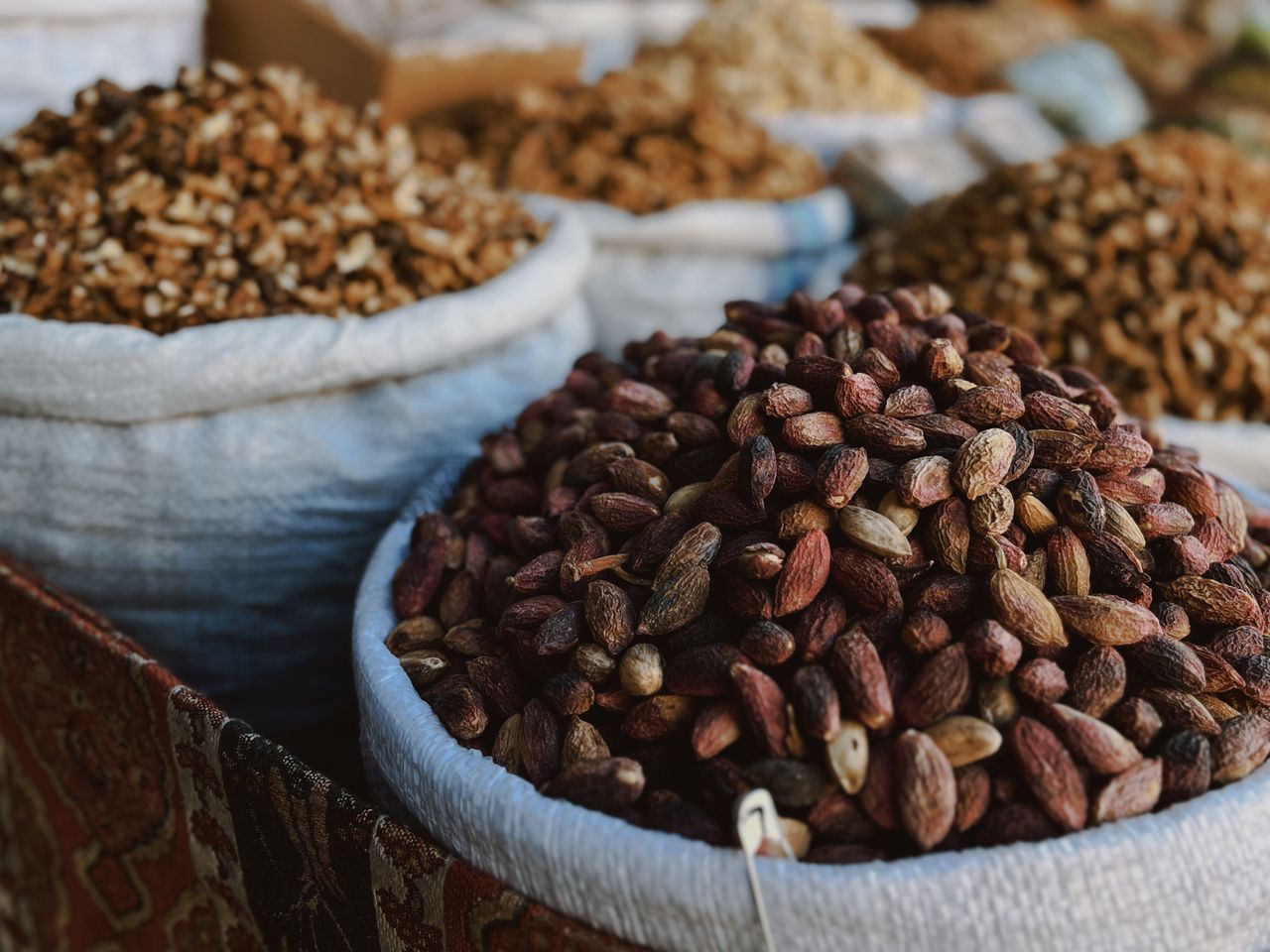 Close-up of assorted nuts in sacks at an outdoor market, showcasing textures and variety.